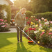 Woman trimming grass around vegetable garden at French countryside farmhouse with CLA200 35cc 4-stroke gas trimmer-minisawpro