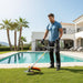 Athletic man trimming grass around luxury villa pool in south of France with GX3G 35cc 4-stroke gas trimmer-minisawpro