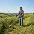Woman clearing overgrown weeds on countryside hillside with S680 portable gas grass trimmer-minisawpro