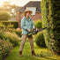 Woman trimming garden hedges with MiniSawPro M12 cordless mini chainsaw – lightweight pruning saw for home use