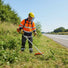 Professional landscaper clearing highway roadside embankment with CLA220 52cc 2-stroke heavy-duty gas grass trimmer-minisawpro