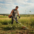 Athletic man clearing overgrown weeds on rural property with GX3G 35cc 4-stroke fuel-efficient gas grass trimmer-minisawpro