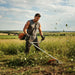 Athletic man clearing overgrown weeds on rural property with GX3G 35cc 4-stroke fuel-efficient gas grass trimmer-minisawpro