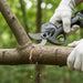 A6-MINISAWPRO electric pruning shears sharp blade close-up cutting thick tree branch – professional cordless pruner