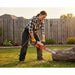 American woman cutting fallen tree in suburban backyard with MiniSawPro S580E corded electric chainsaw and orange power cord