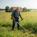Elderly man clearing thick weeds on German countryside farm with MIP2J11 52cc 2-stroke gas grass trimmer-minisawpro