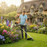 Man trimming flower bed edges in English cottage garden with MIP1399 35.8cc 4-stroke gas grass trimmer-minisawpro