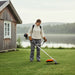 Woman maintaining Scandinavian lakeside summer house lawn with CLA200 35cc 4-stroke efficient gas grass trimmer-minisawpro