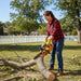 American woman cutting storm-fallen branches in Midwest suburban backyard with 2J000 25.4cc petrol chainsaw-minisawpro