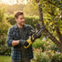Man trimming tree branches in backyard garden with MiniSawPro M13 cordless mini chainsaw – lightweight pruning saw