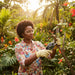 Woman pruning tropical plants in vibrant garden with A3-MINISAWPRO cordless electric pruning shears